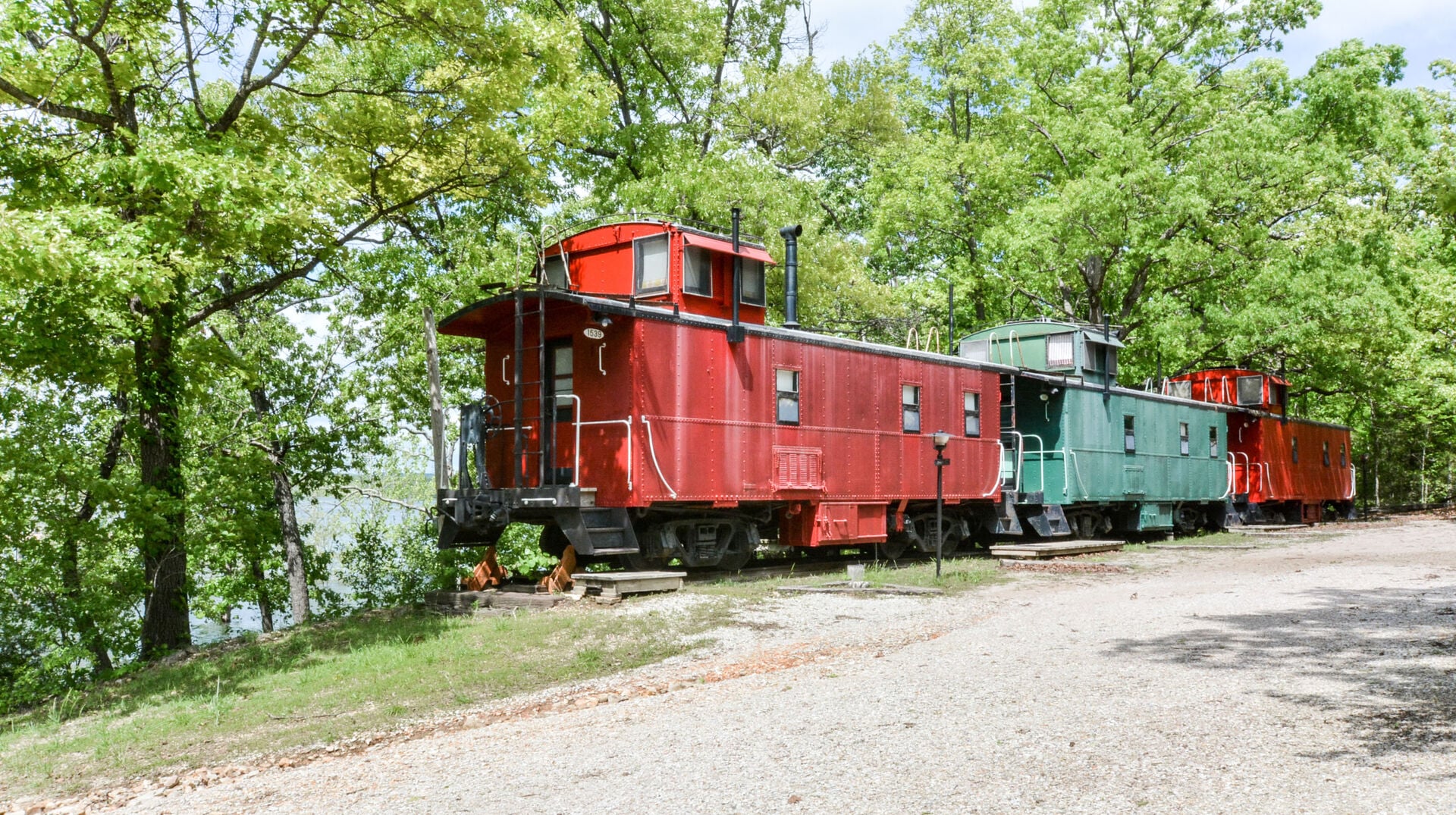 Three historic Caboose Junction cabooses on a wooded slope beside Table Rock Lake